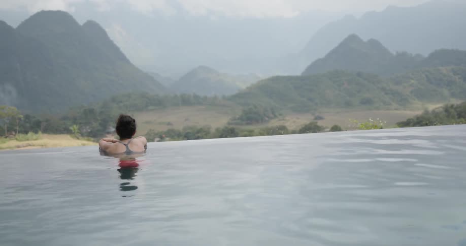 A woman rests at the edge of the infinity pool