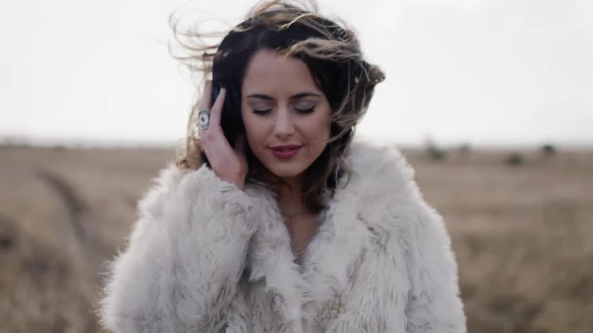 Woman listens to headphones in a rural field
