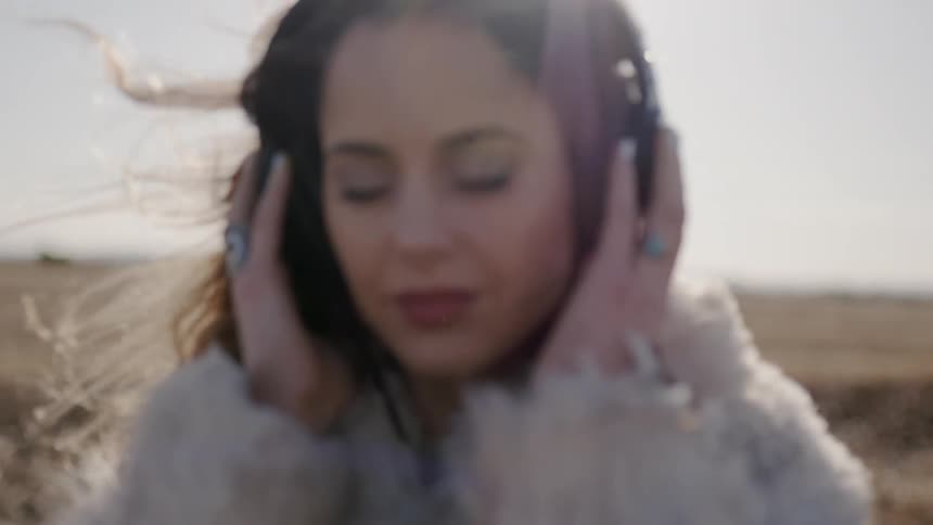 Woman listens to headphones on a windy and sunny day