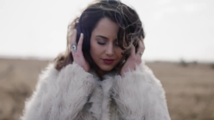 Woman listens to headphones outside on a windy day
