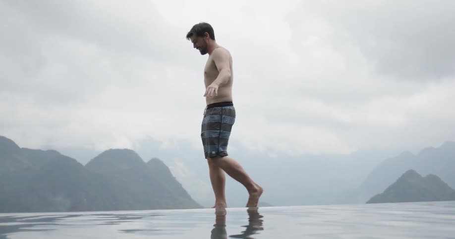Man in swim shorts walks through the shallow water