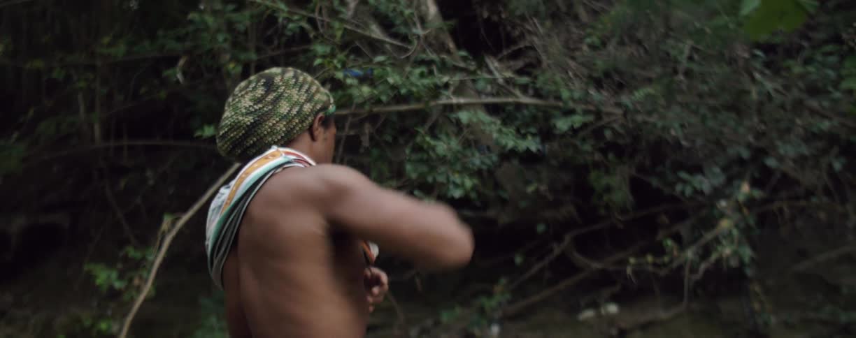 A man tanks off his tank top by the river