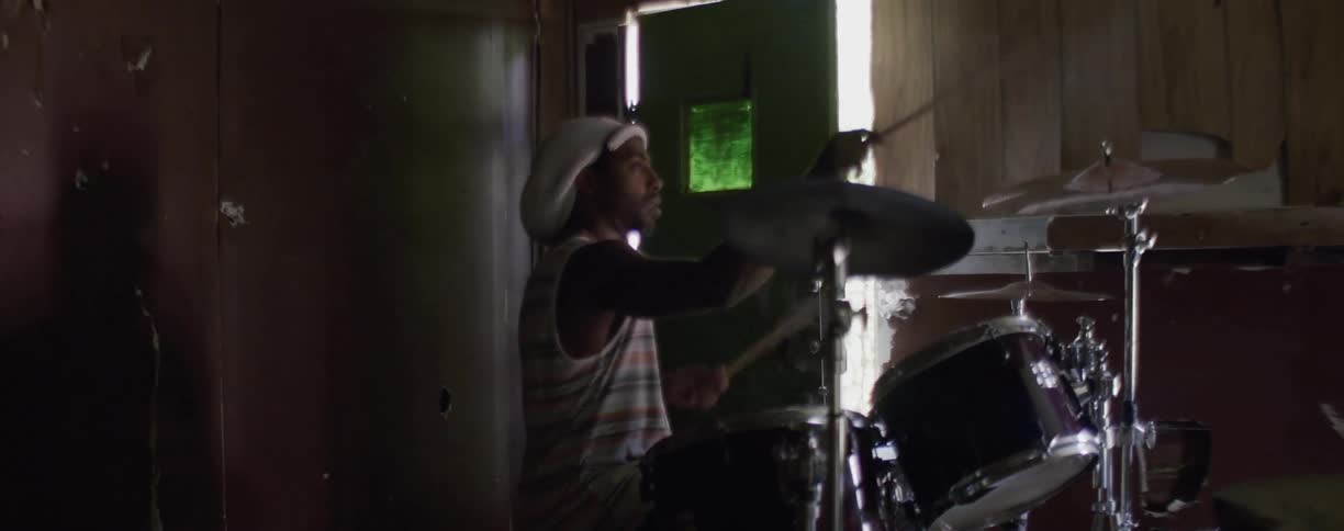 A man is playing drums in the dark room