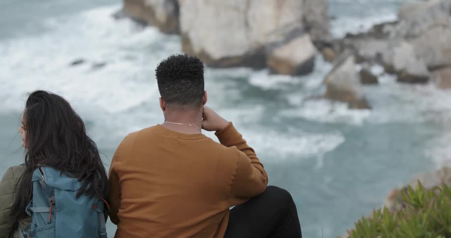 A man and woman sit on the cliff