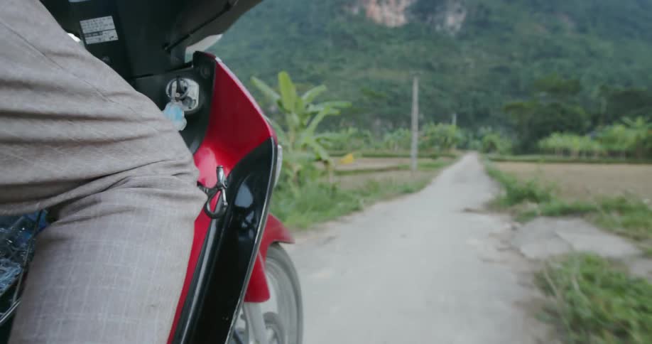 A red scooter rides on a narrow road