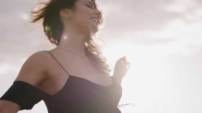A woman twirls around on a windy day