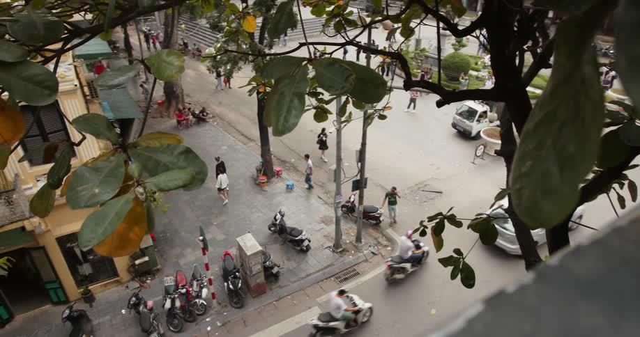 Pedestrians and traffic navigate a busy corner in a city in daylight