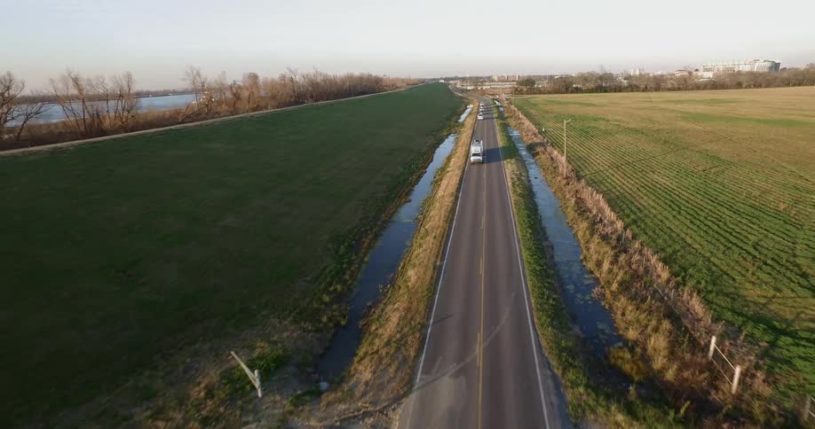 Vehicles drive on a rural road at sunset