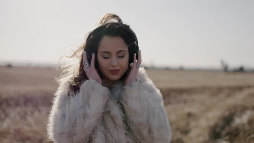 Woman wears a fur coat as she stands in the field
