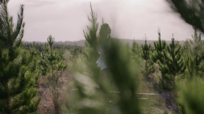 Woman stands in a field of small trees