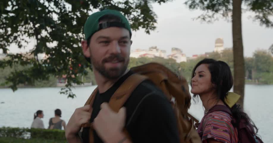 Man and woman walk with backpacks in a park