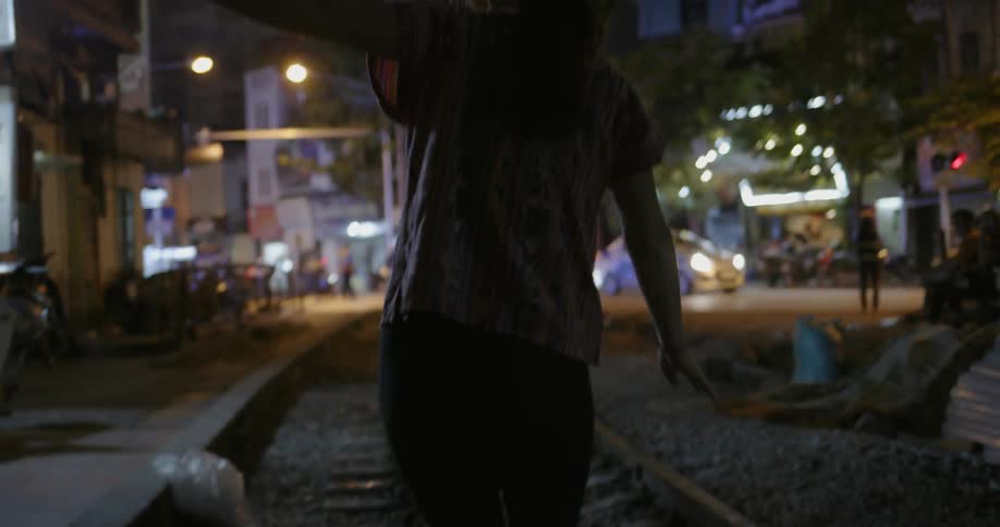 Woman balances herself as she walks on a railway track