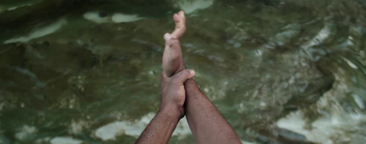 A man stretches his wrists above the flowing water