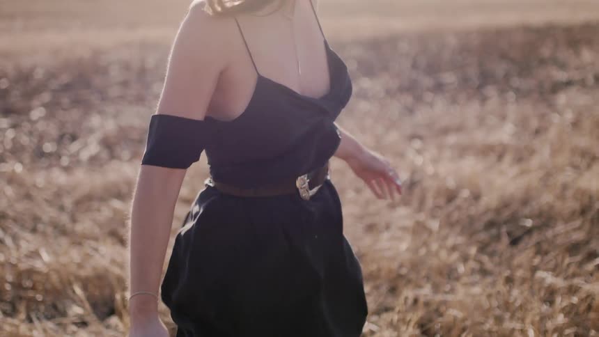 Woman wears a black dress as she stands in a field