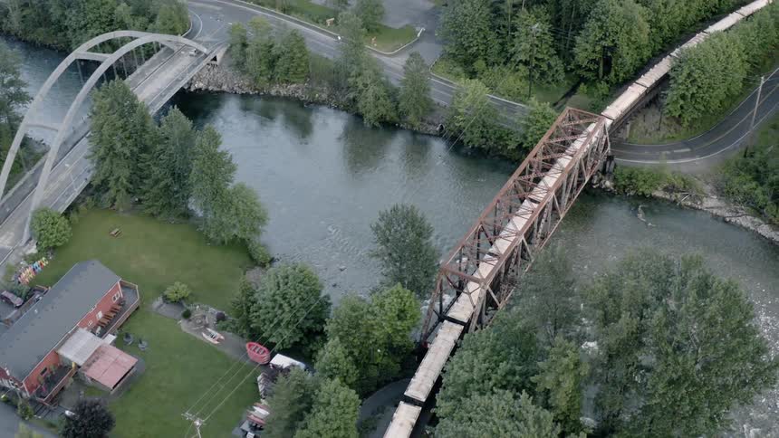 Train travels down the tracks over a bridge