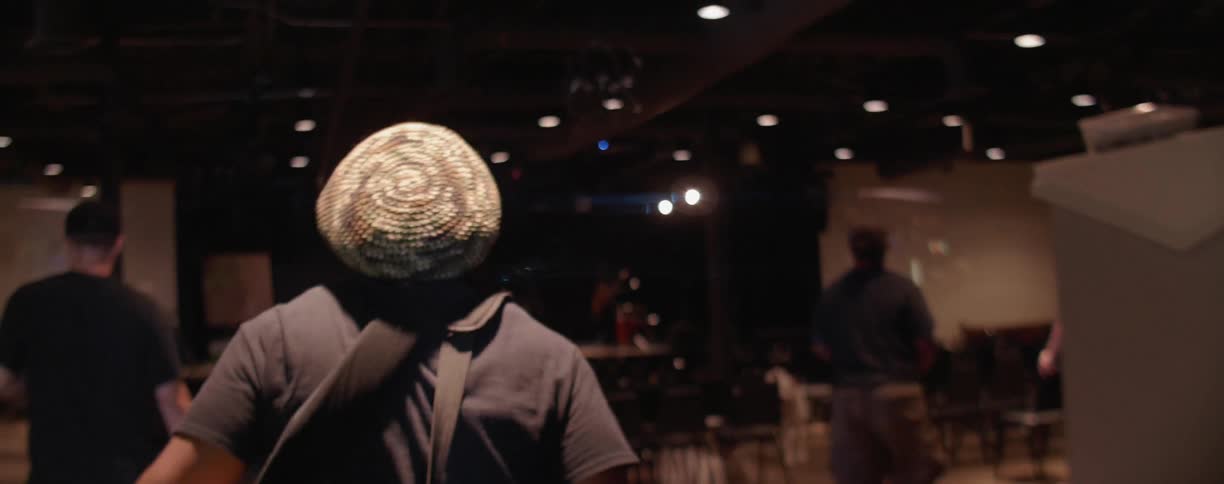 The man walks into the hall towards the stage