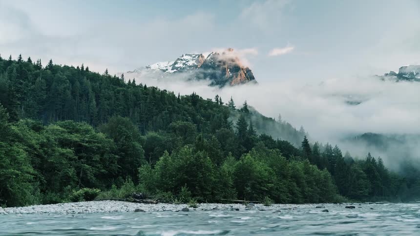 Clouds and fog pass above the flowing river - 4K Time Lapse