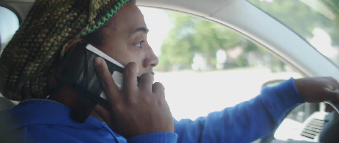 Man is talking on cell phone while driving in car on sunny day