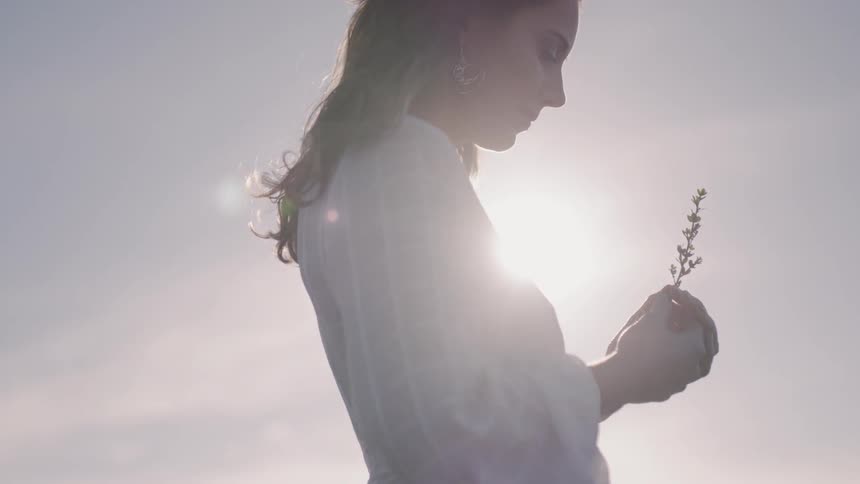 A woman holds a picked flower