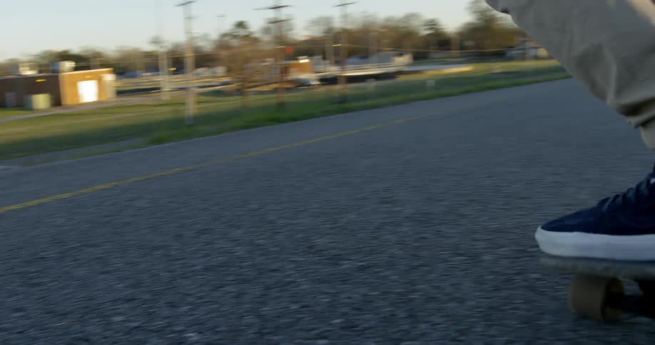 A man rides his skateboard down the small road