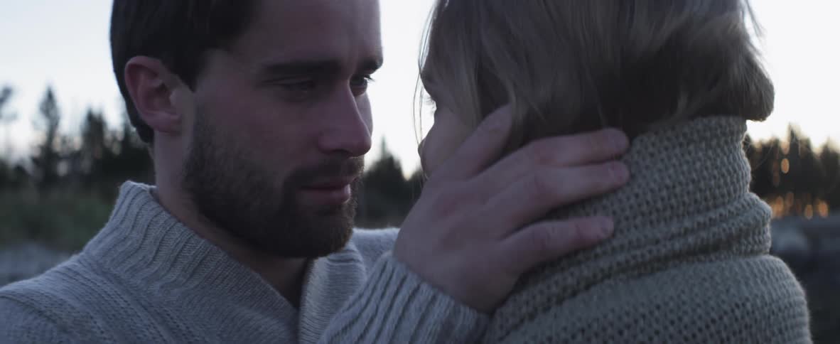 Man and woman standing close together on a cloudy day