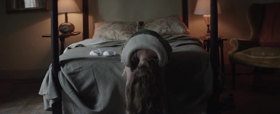 A woman hunched over on a bed