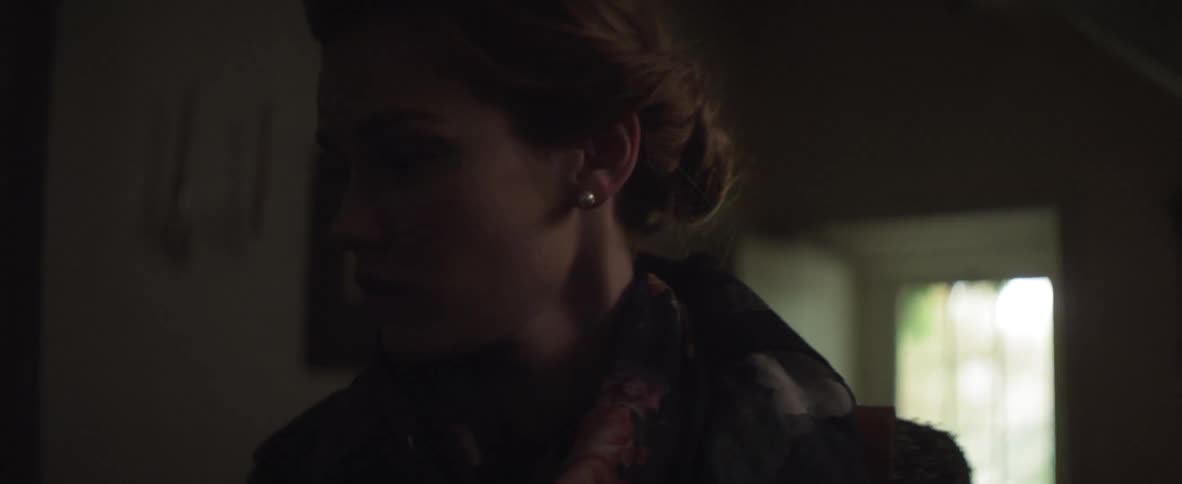 Woman standing in a dark room turns and walks off