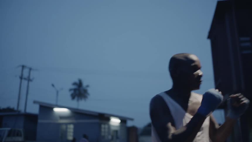 Man practices boxing jabs outdoors near a building