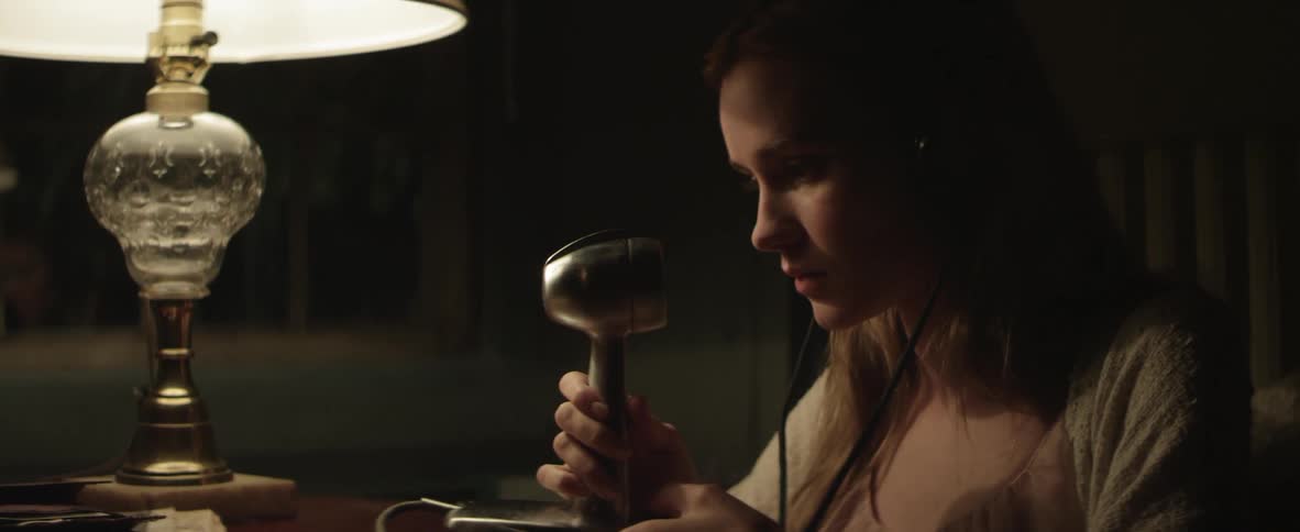 A woman sits at a desk wearing headphones and talking on a radio