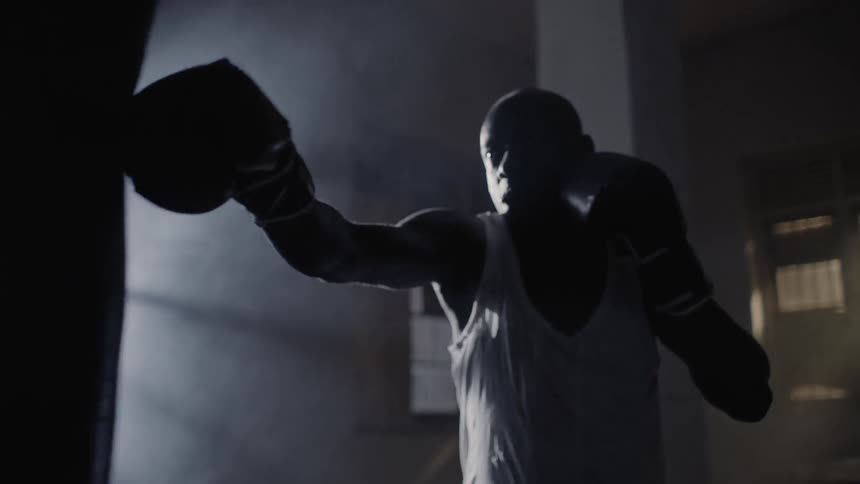 Man boxing a punching bag next to sunny window