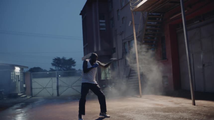 A man is shadowboxing in the alley at sunset