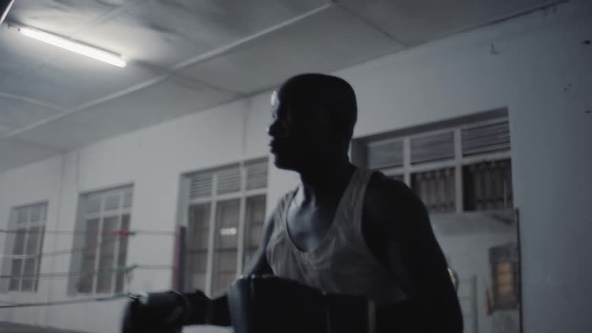 Man hits punching bag in boxing gym