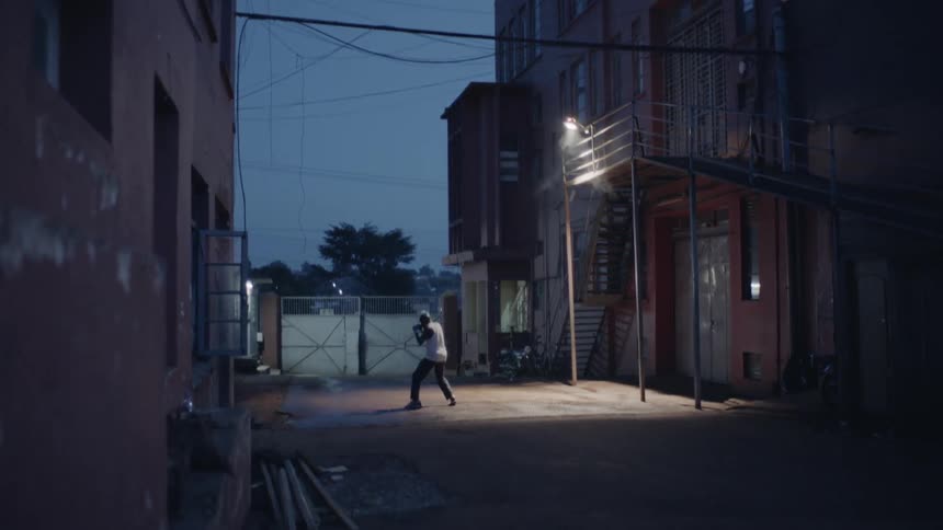 Man is practicing boxing outside city building at night