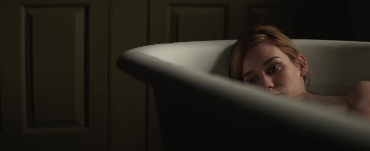 A woman in the bathtub with her head resting against the back of the tub