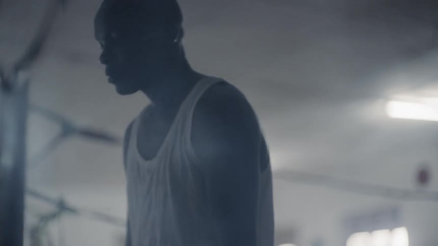 Man stands in a gym as he looks at a broken mirror