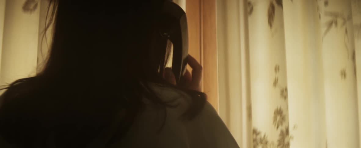 Woman on the phone walks over to a window