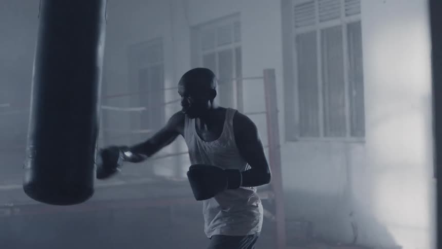 Man is boxing a punching bag in gym training room