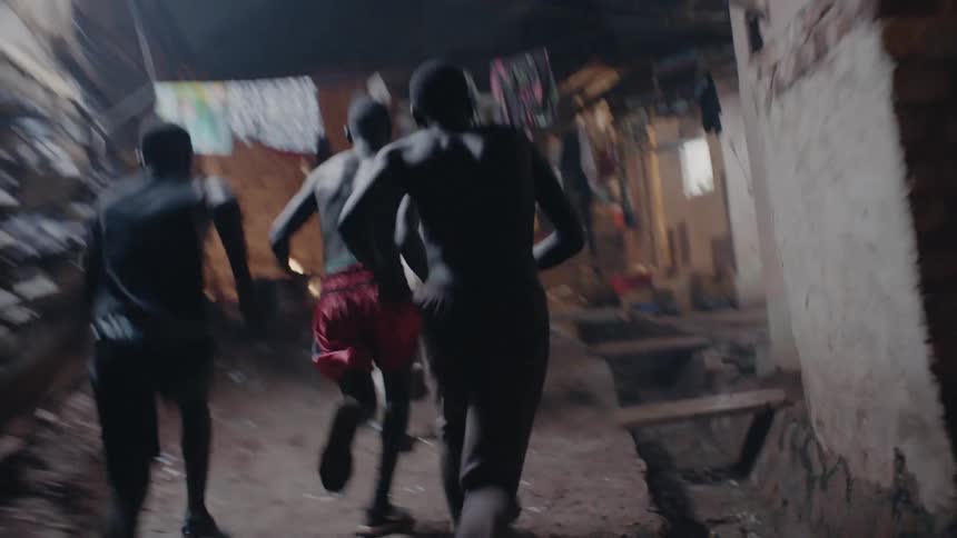 Three men run on a path near the buildings at night