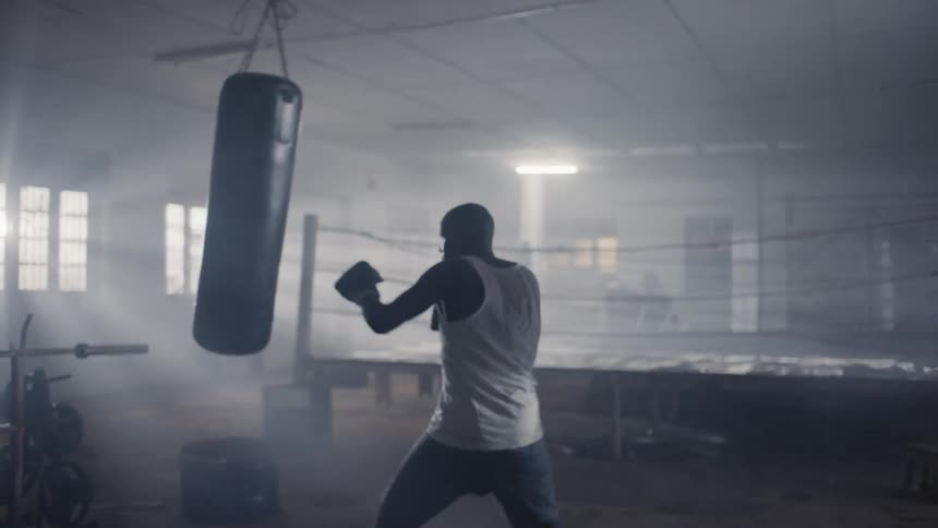 Man is boxing a punching bag in gym training room