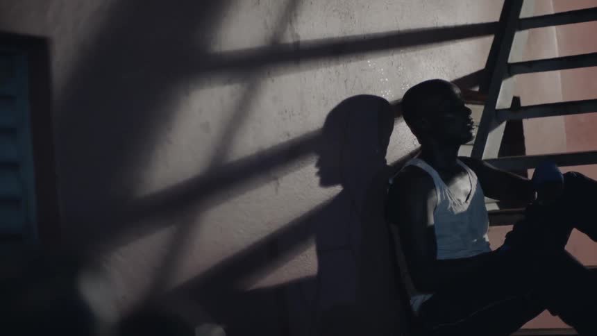 A man sits against a wall catching his breath