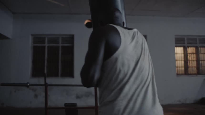 A man walks up punching the heavy bag