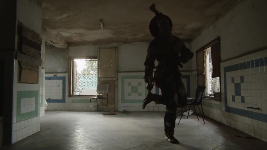 A person is dancing in the dark room in a costume