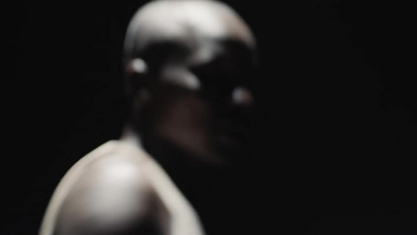Man wearing boxing gloves is spinning around in the dark