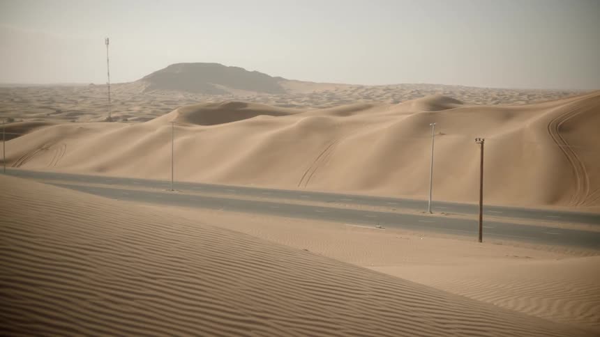 Cars traveling on highway in between sand dune hills