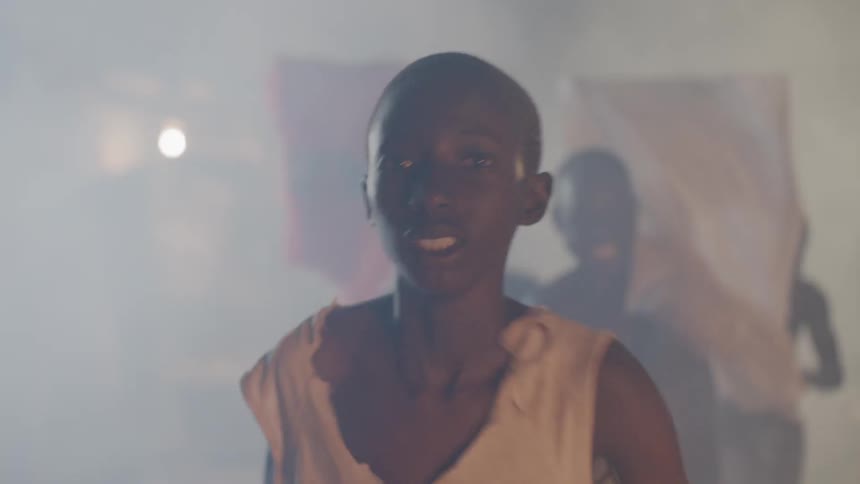 Men push clothes out of the way as they run in the mist