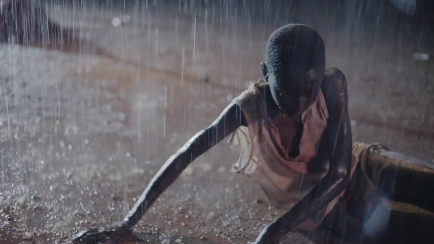 Teenage boy lies on the ground in the rain