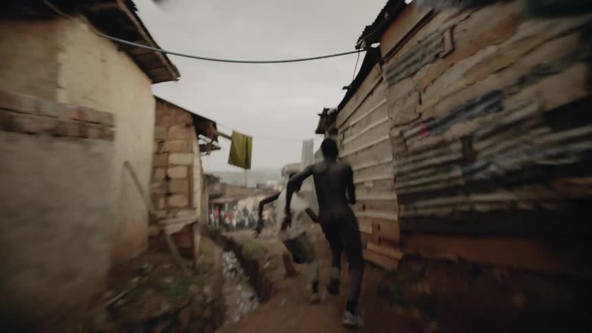 A man chases a boy past clothes lines and homes before catching him