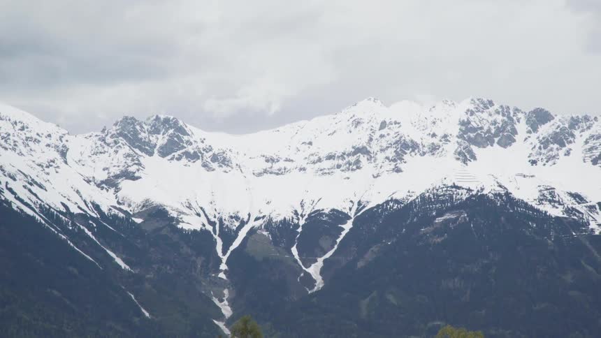 Large mountains partially covered in snow on cloudy day