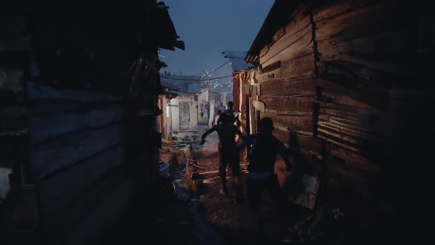Group of men run between the buildings under the night sky