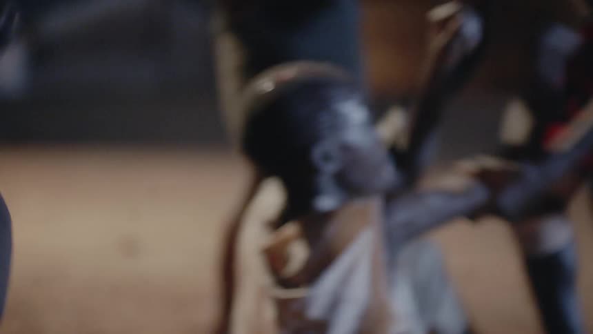 A group of people beat up a man in the dirt
